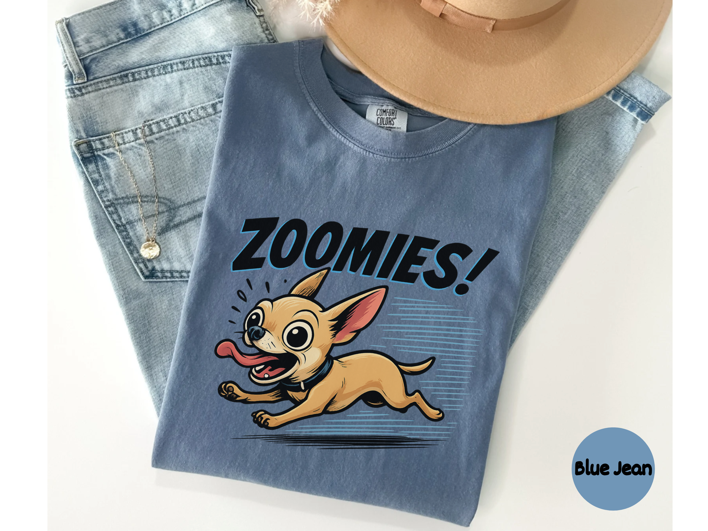 Blue chihuahau shirt with 'Zoomies!' graphic and cartoon dog, displayed with jeans and a hat.