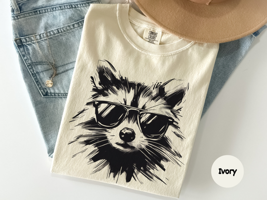 Humorous raccoon with sunglasses illustration on unisex white t‑shirt perfect for everyday wear