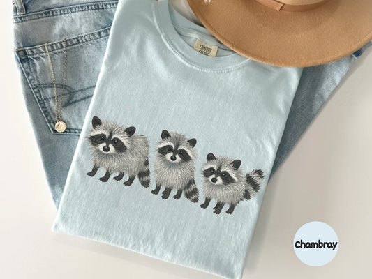 Cute raccoon trio graphic t shirt featuring three fluffy raccoons standing together with expressive faces and soft fur detail perfect for woodland animal lovers
