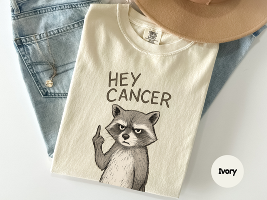 Hey cancer graphic tee with an angry raccoon illustration showing defiant gesture designed for people who use sarcasm and humor to face tough times