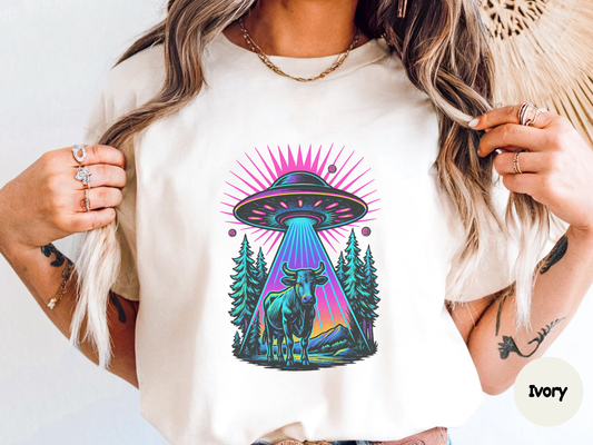 Psychedelic alien abduction shirt showing a glowing UFO lifting a cow with vibrant colors and surreal forest background