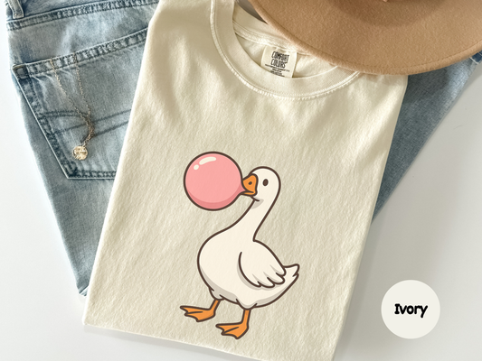 Close up of a black shirt showing a white goose chewing bubble gum with a pink bubble in a cartoon style designed for fans of cute animal art meme humor and fun casual fashion