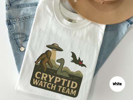 cryptid watch team shirt graphic showing bigfoot loch ness monster ufo and flying cryptid illustrated in vintage paranormal badge style on black background
