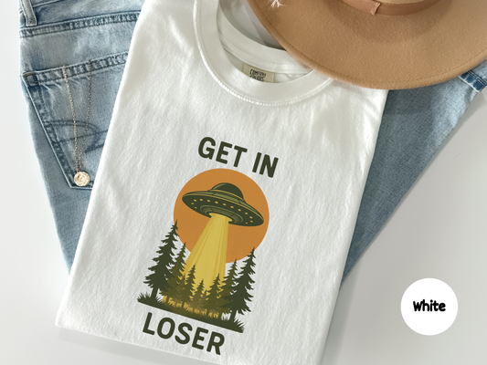 get in loser ufo shirt graphic showing flying saucer abducting forest trees with glowing beam and retro sci fi sunset background