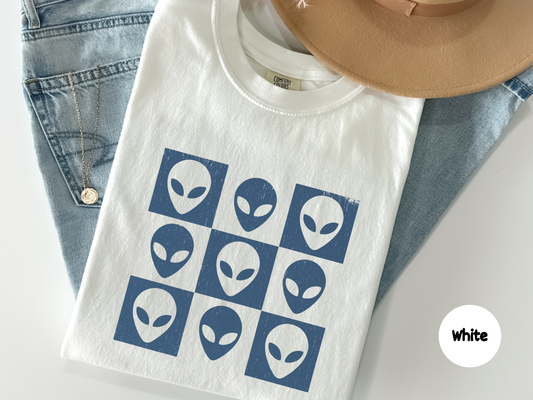 Alien face grid pattern graphic t shirt featuring nine minimalist blue alien heads in a square layout on a black background with a distressed texture aesthetic