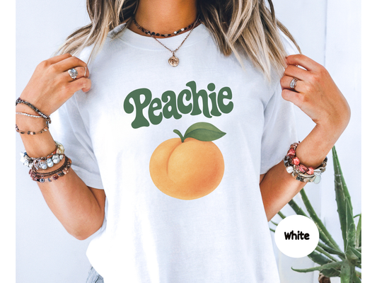 Peach fruit graphic t shirt with soft orange peach illustration and green leaf paired with retro peach lettering on black background